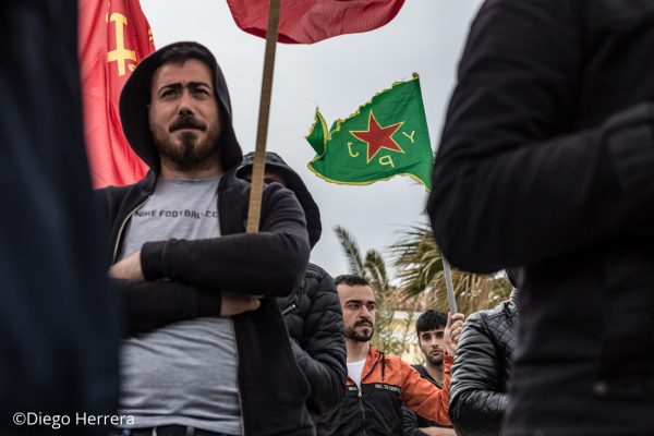 Un hombre sostiene una bandera de la YPJ durante una manifestación por las calles de Lavrio